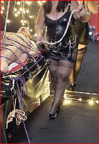 Latex-clad domme performs CBT on naked male slave Latex-clad domme performs CBT on naked male slave