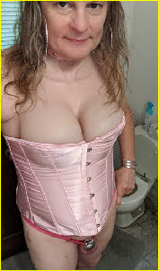 Cross-dressing sissy Chrissy in pink corset and clit cage